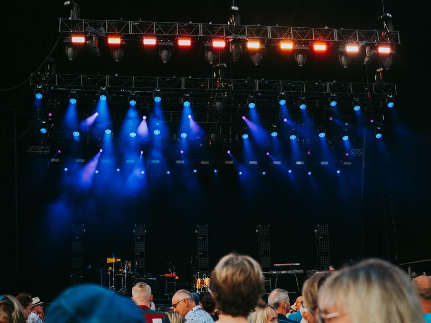 Concert stage lit by blue and orange stage lights with an audience in front